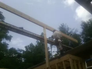 Carpenter setting a ridge beam over a new addition frame — Ice Dam Removal by Roofing Brothers in Clinton